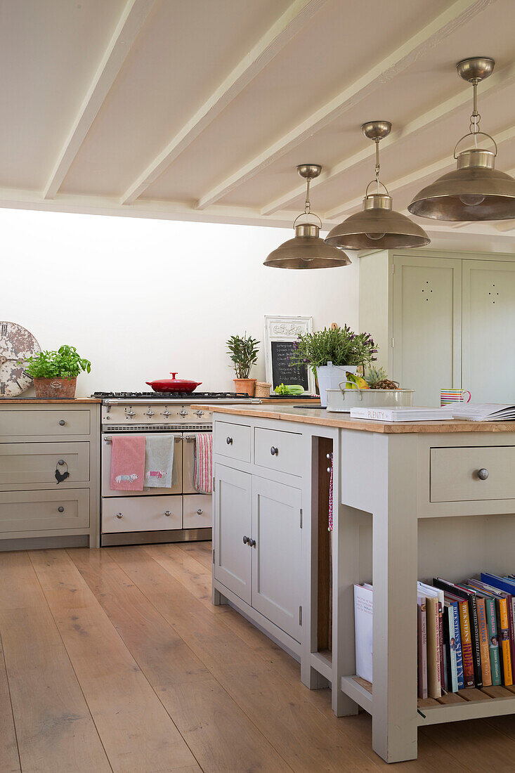 Messing-Pendelleuchten über der Kücheninsel in einem Bauernhaus in East Dean, West Sussex, Großbritannien