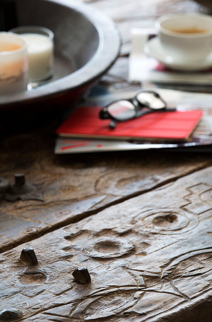 Brille und Notizbuch mit Kerzen und Teetasse auf geschnitztem Holztisch in Londoner Wohnung, England, UK