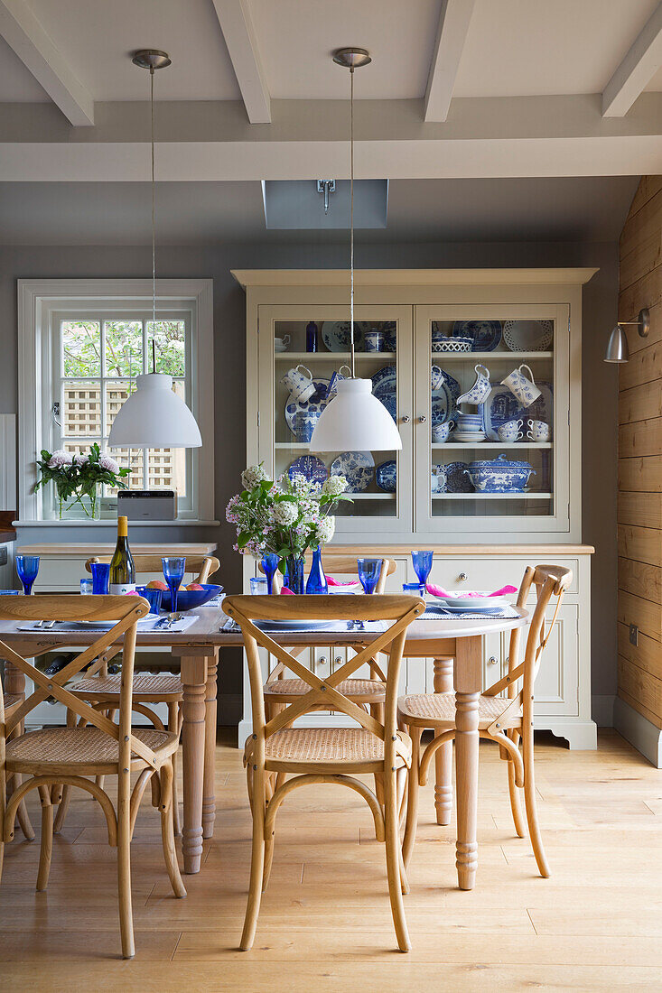 Blaues Glasgeschirr auf dem Esstisch unter Pendelleuchten in einem Haus in Surrey, England, UK