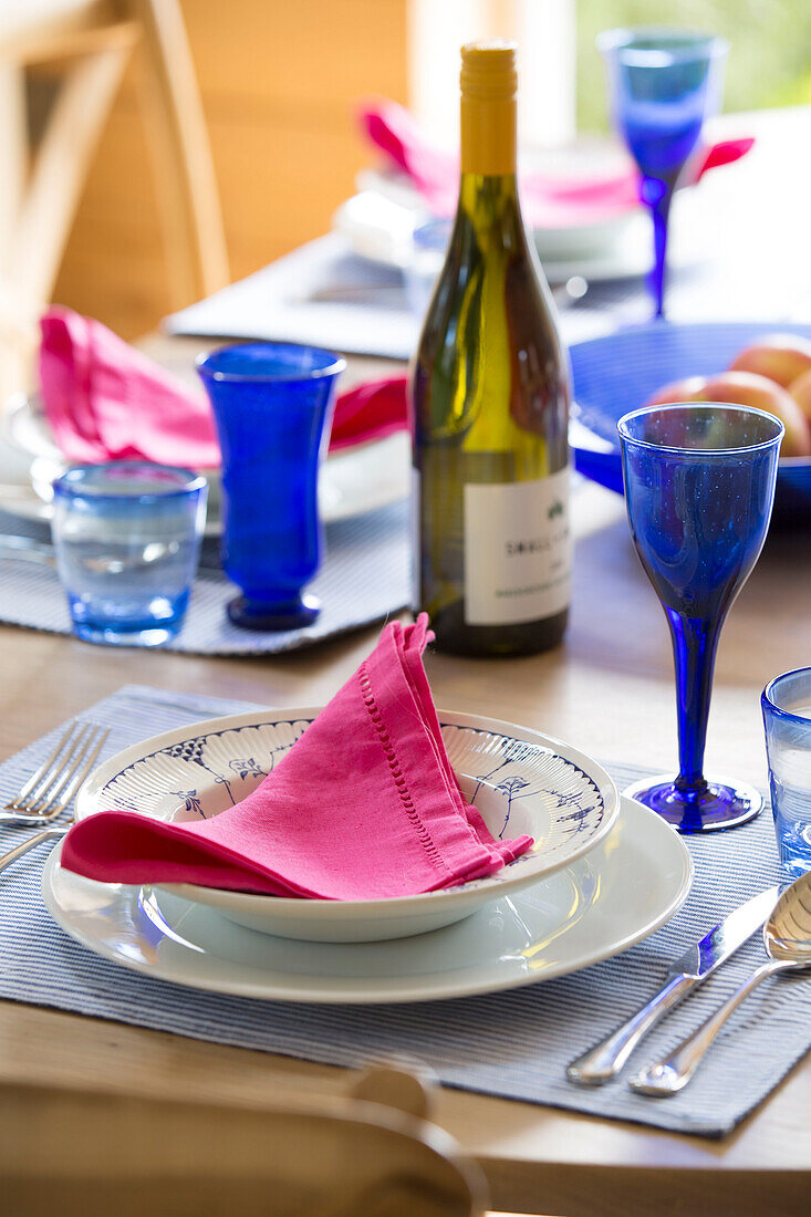 Blaue Gläser mit rosa Servietten auf einem gedeckten Tisch in einem Haus in Surrey, England, UK