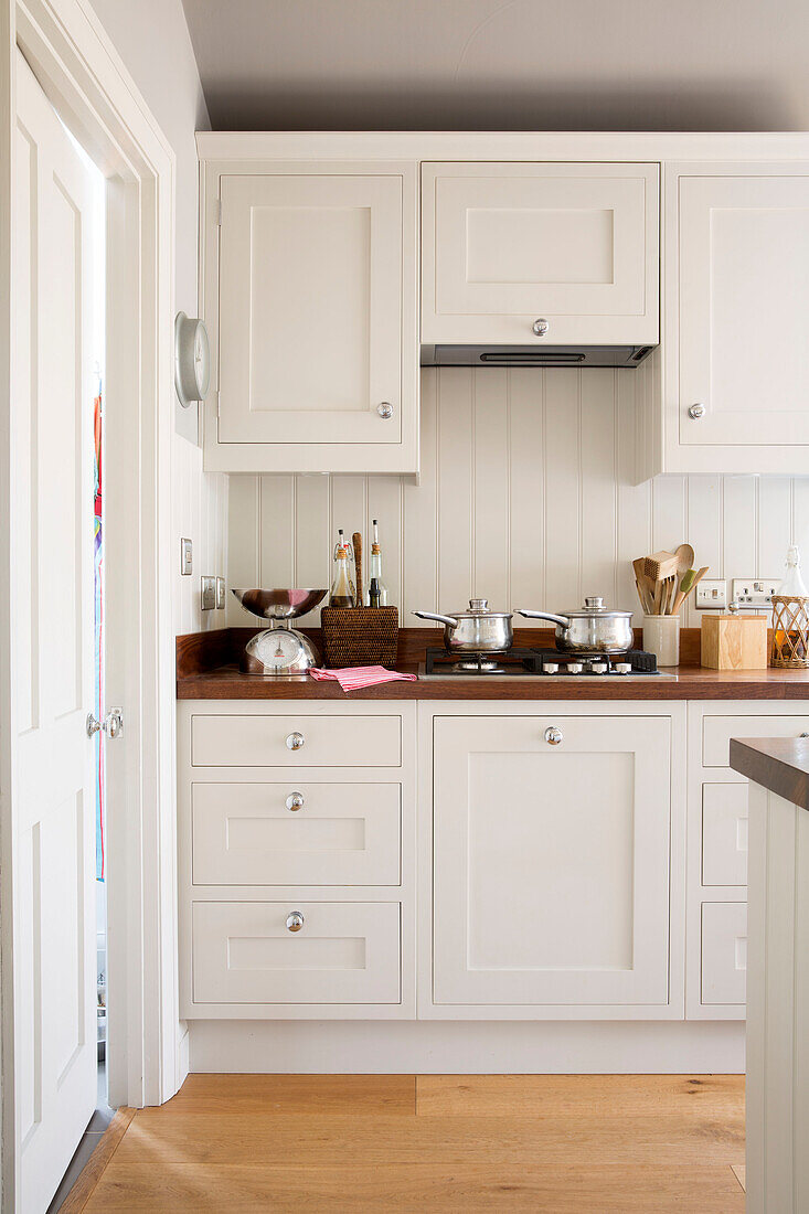 Töpfe auf einem Gaskochfeld in einer weißen Einbauküche in einem Haus in Surrey, England, Vereinigtes Königreich