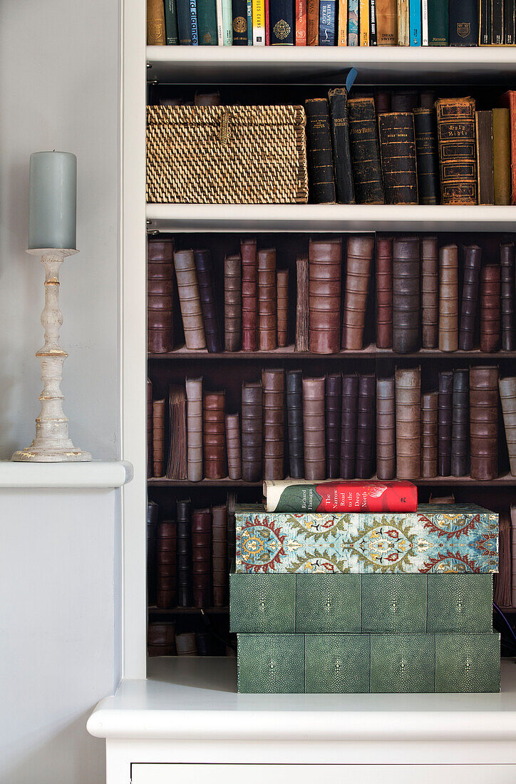 In Leder gebundene Bücher mit Nähkorb auf Regalen in einem Haus in Surrey, England, UK