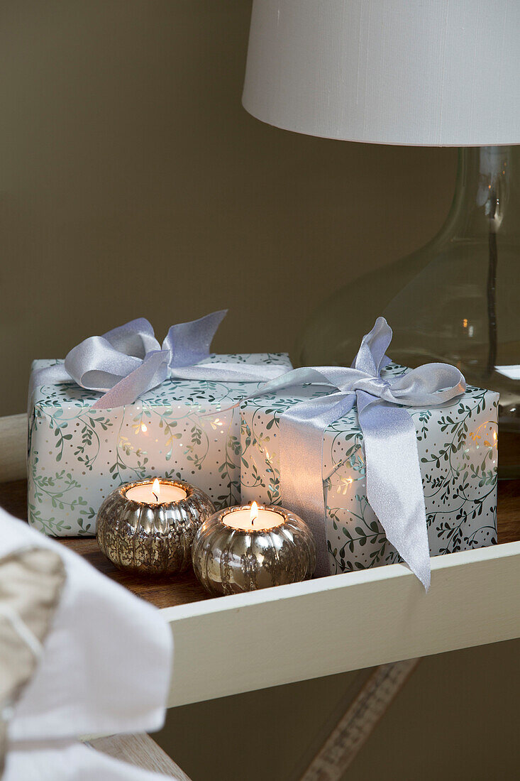 Eingepackte Geschenke und Teelichter auf dem Nachttisch im Schlafzimmer in Chobham Surrey England UK