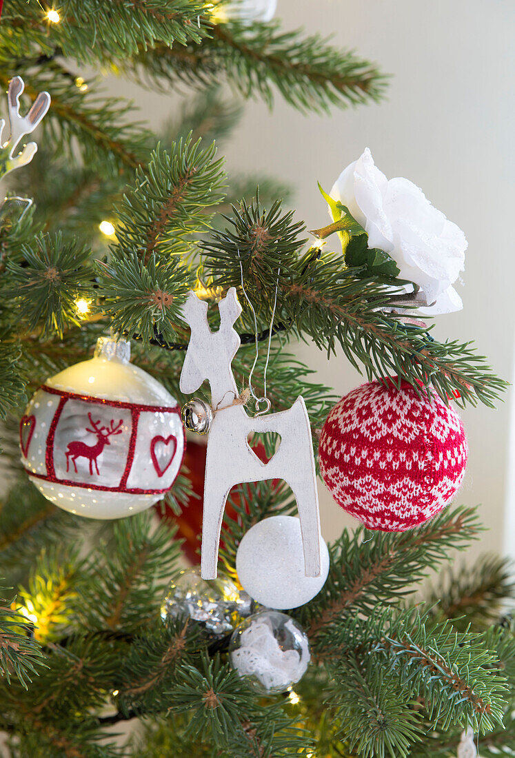 Cut-out reindeer and baubles with white rose and fairylights on Christmas tree in Surrey home   England   UK