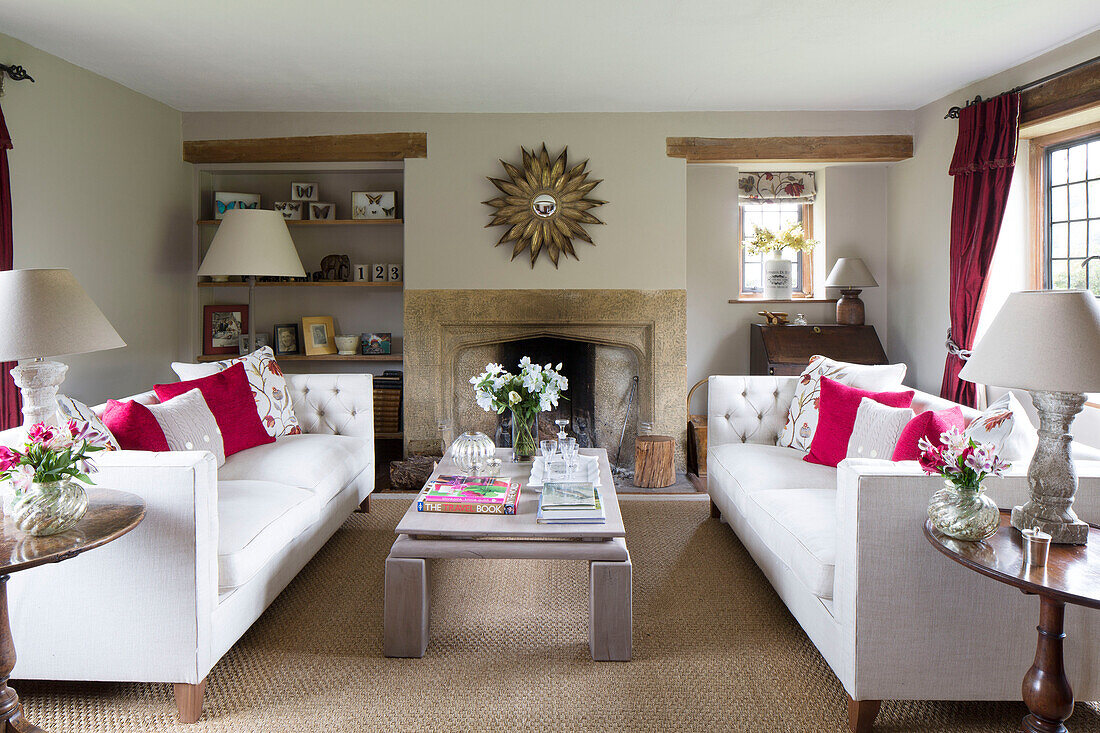 Pair of white sofas with low table and sunburst mirror in Sussex farmhouse   England   UK