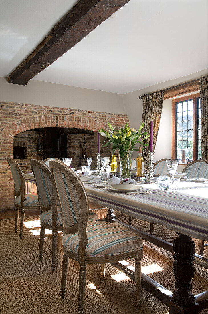 Cut lilies in beamed Sussex dining room with exposed brick fireplace   England   UK