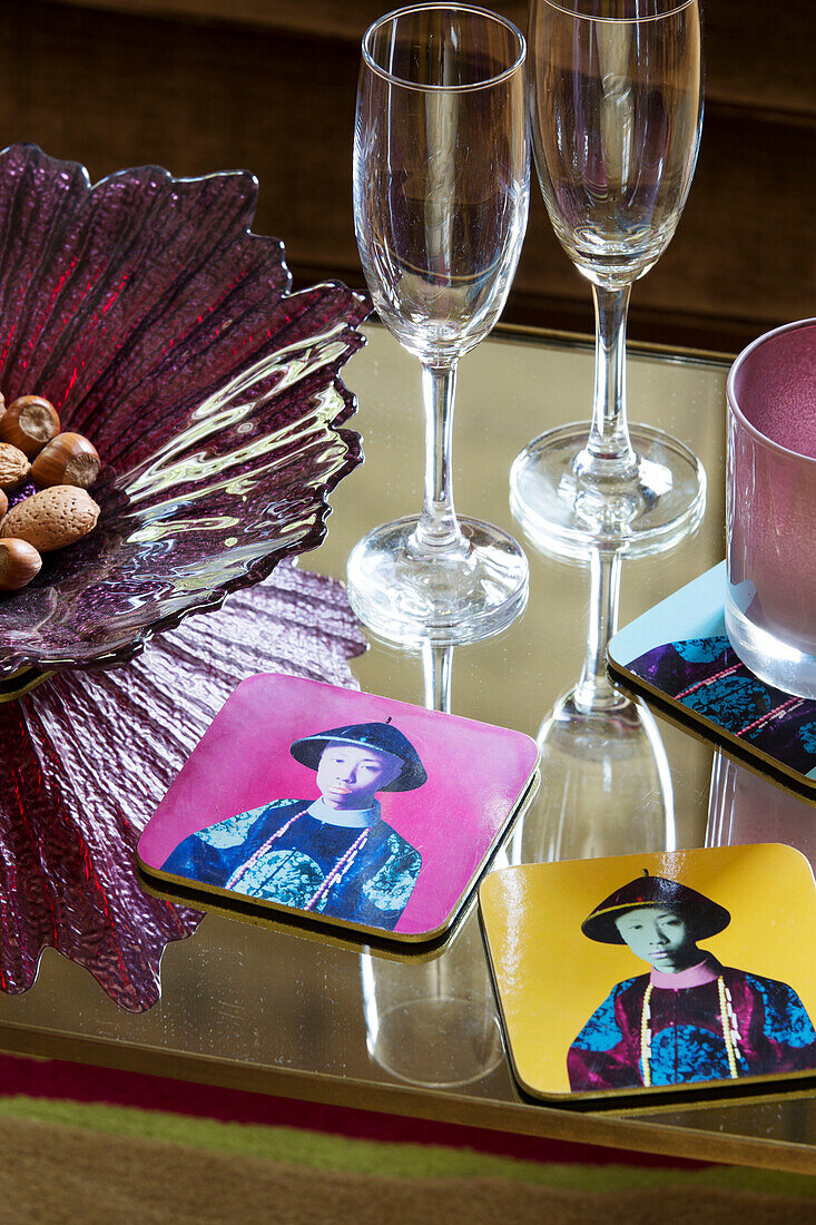 Wineglasses and coasters with coloured glass bowl on tabletop in London townhouse   England   UK