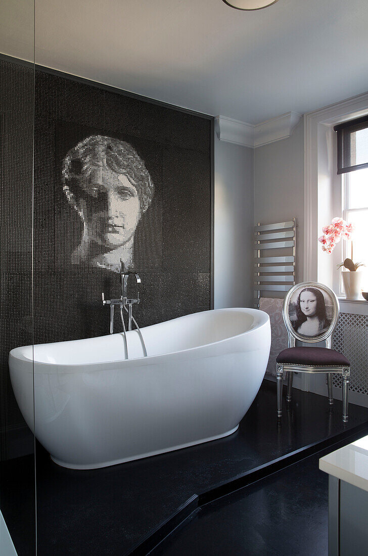 Female head on feature wall above freestanding bath in London townhouse   England   UK