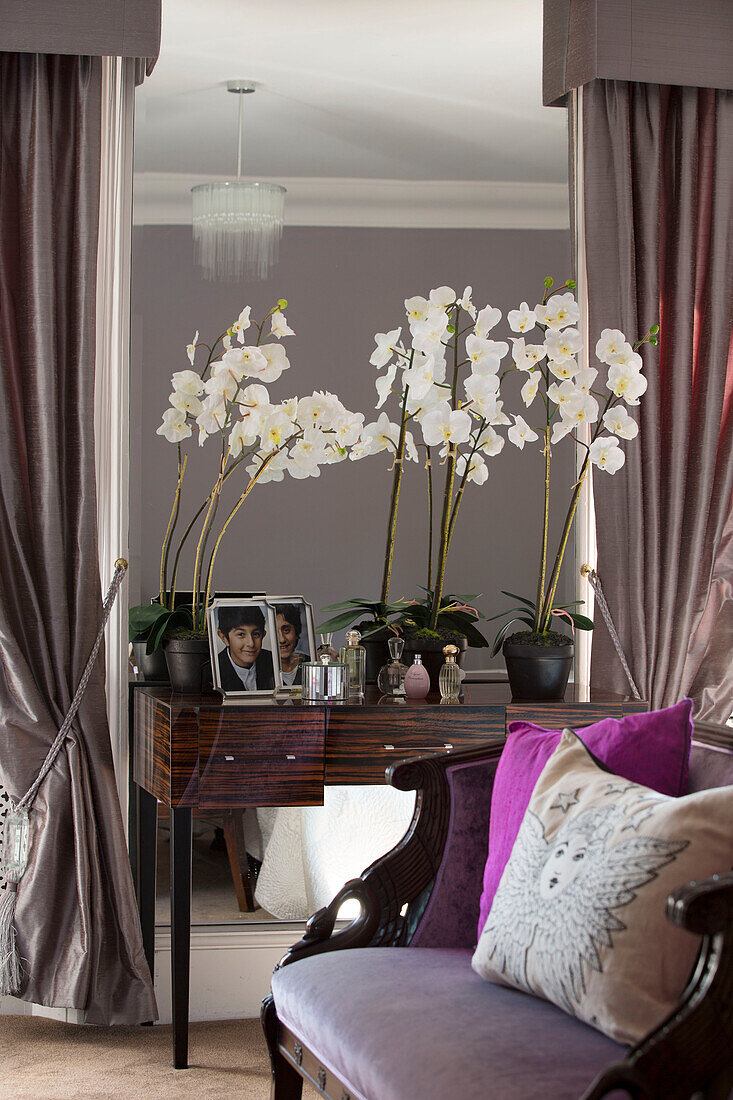 Orchideen auf Schminktisch mit verspiegelter Wand im Schlafzimmer eines Londoner Stadthauses England UK
