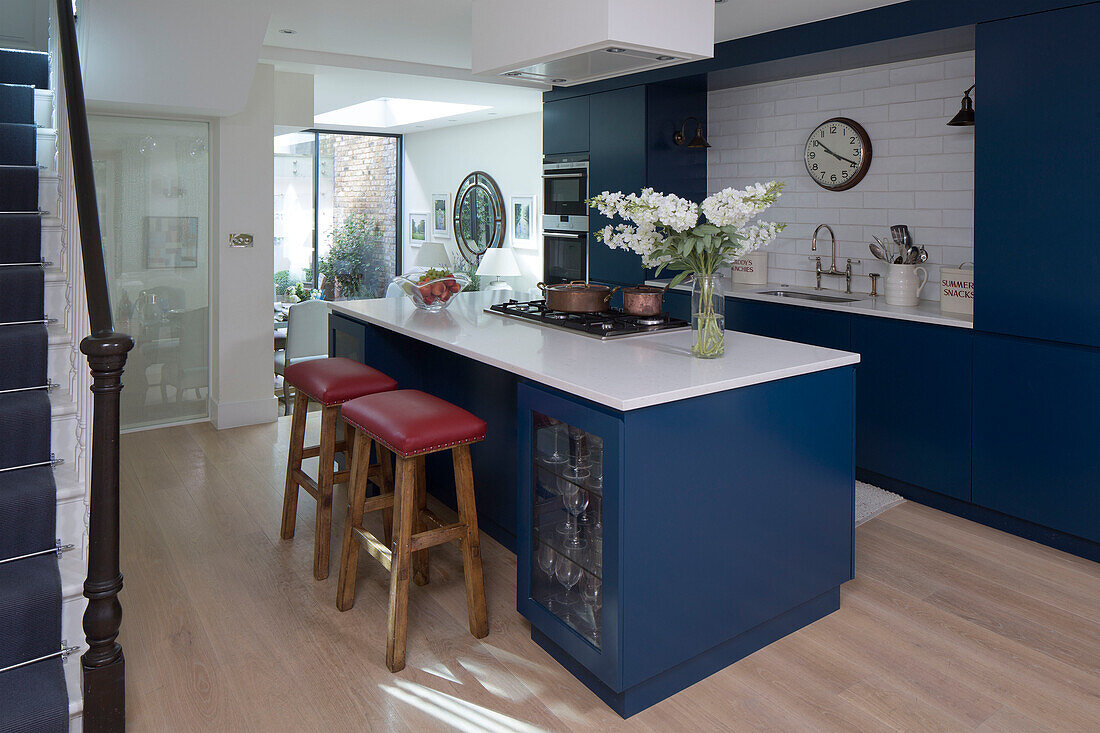 Schnittblumen auf blauer Kochinsel mit Barhockern in offener Küche eines Londoner Stadthauses England UK
