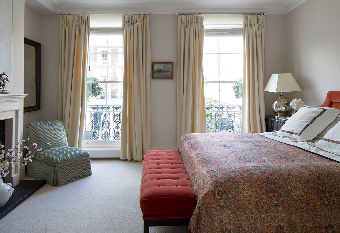Cremefarbene Vorhänge an französischen Fenstern mit geknöpftem Sitz am Fuß des Doppelbetts in einem Londoner Stadthaus England UK