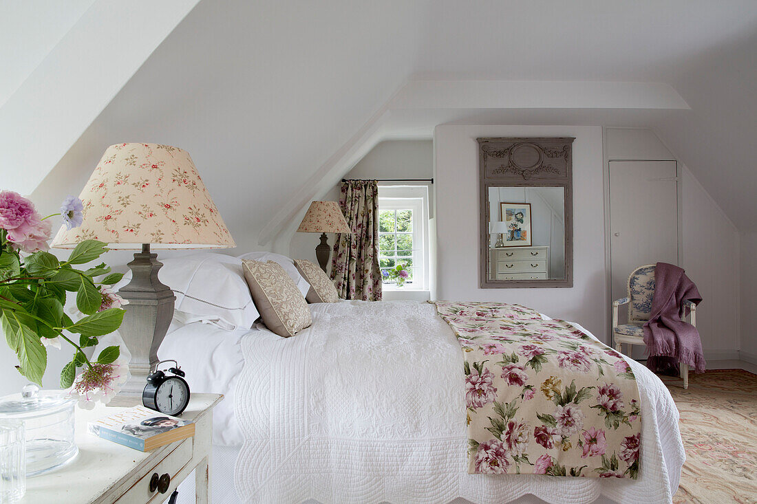 Lampenpaar am Bett mit geblümter Bettdecke in einem Landhaus in Sussex, England UK