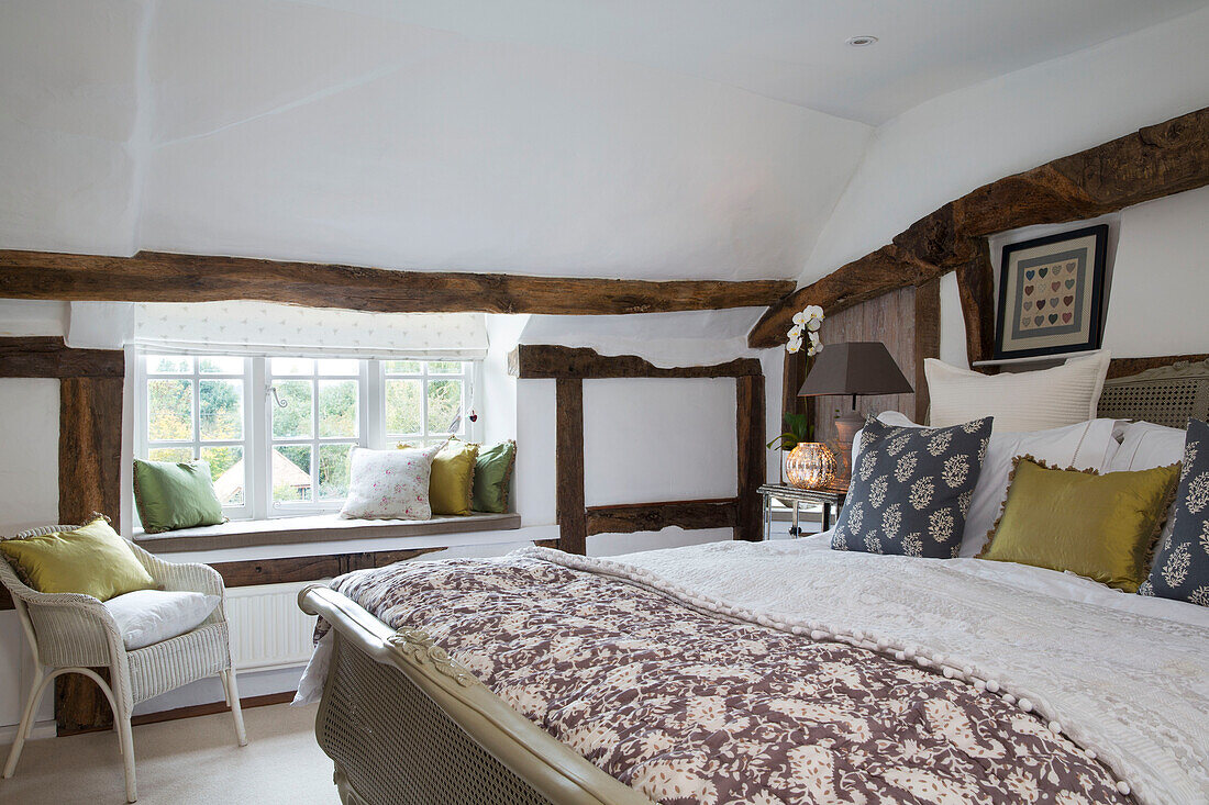 Brown patterned bedspread and window seat in timber framed Surrey cottage England UK