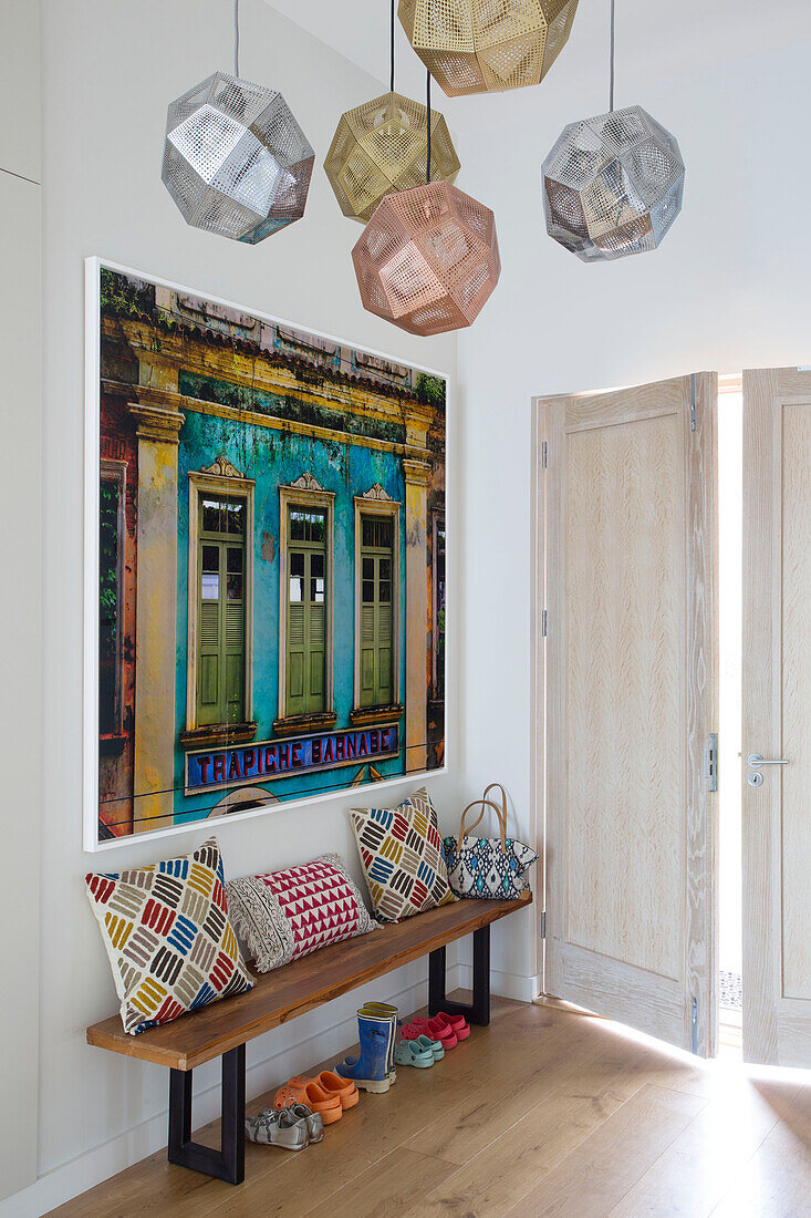 Art canvas above bench with cushions in hallway with metallic lampshades Lechlade home Gloucestershire England UK