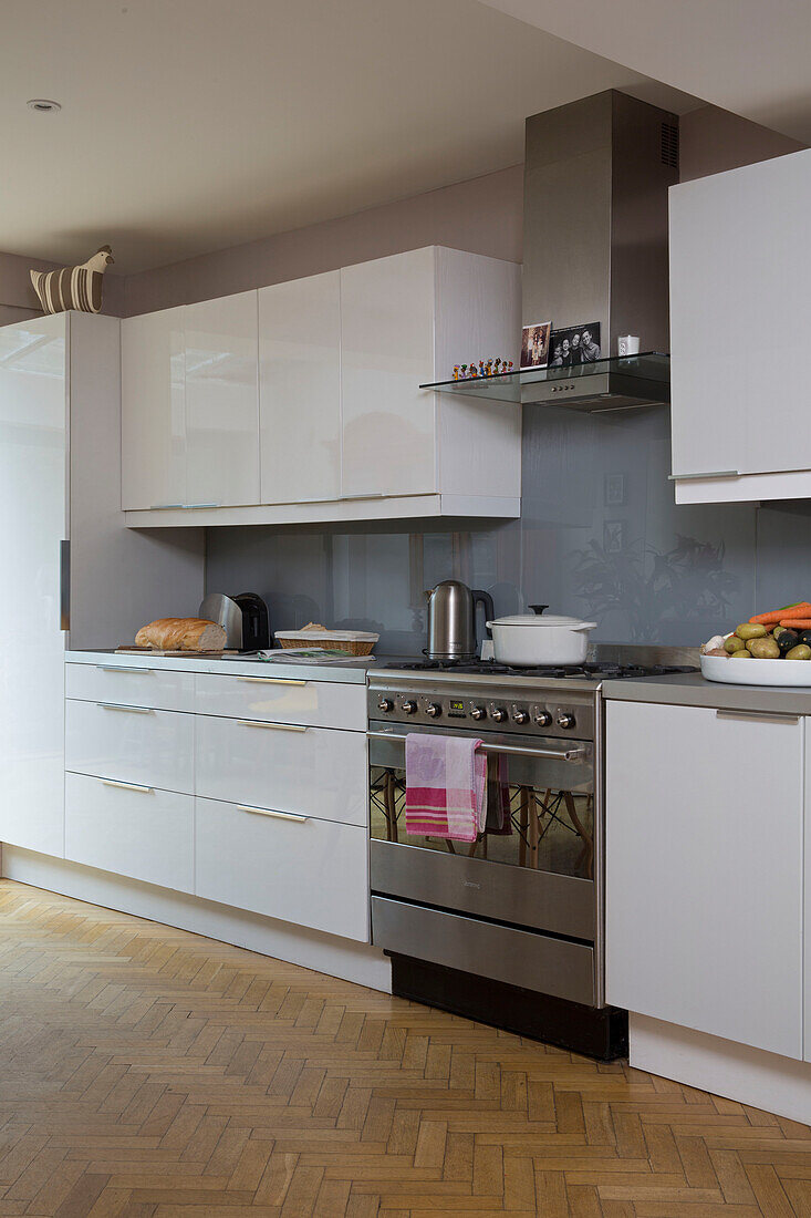 Dunstabzugshaube und Backofen aus Edelstahl in einer weißen Einbauküche in einem Einfamilienhaus im Südwesten Londons UK