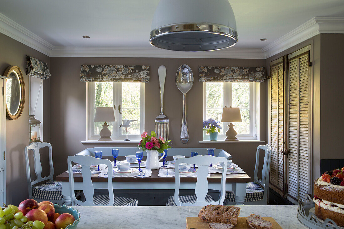 Blaue Weingläser auf einem Esstisch mit karierten Sitzkissen in einem Landhaus in Wokingham, Berkshire, Großbritannien