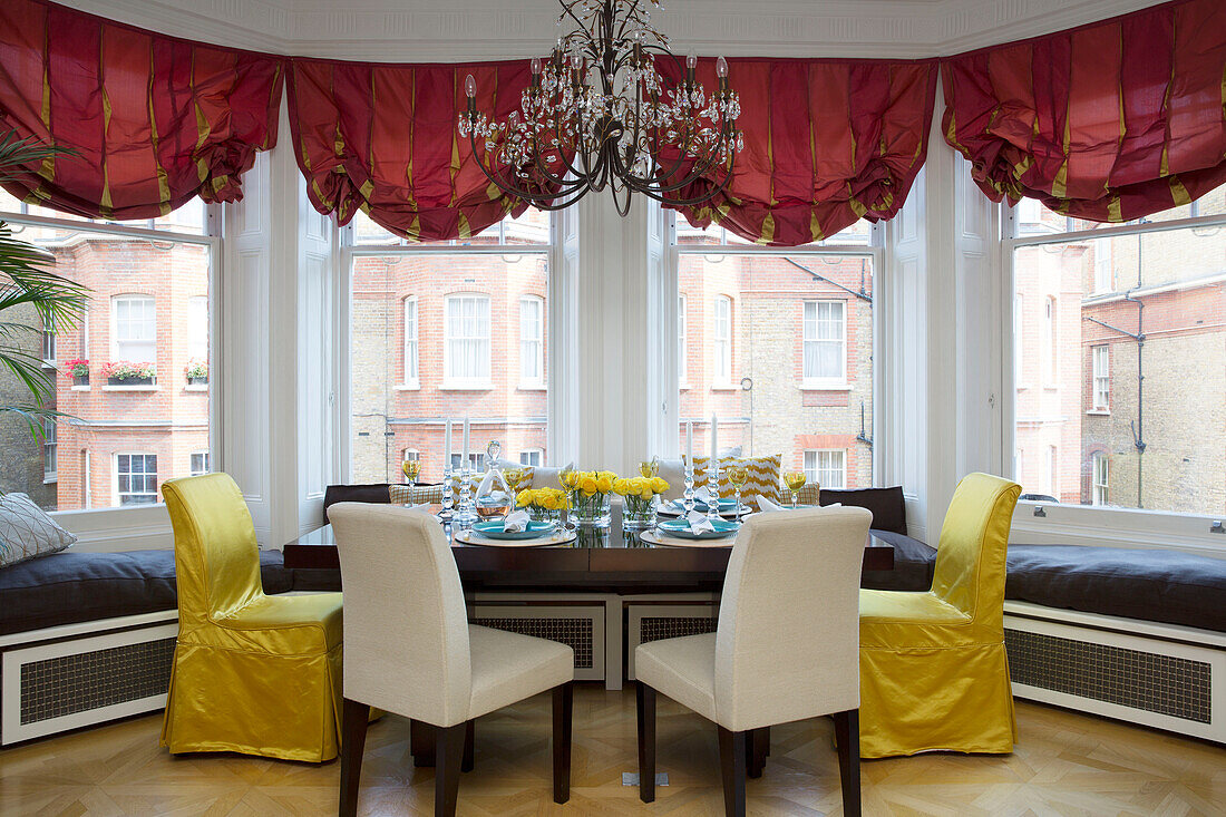 Goldene und cremefarbene Esszimmerstühle am Tisch mit Fensterplatz in einem Londoner Stadthaus UK
