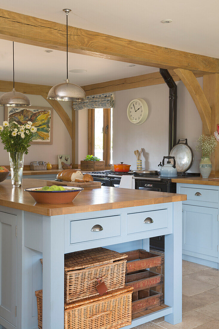 Storage baskets and crates in blue island unit in timber framed Surrey kitchen England UK