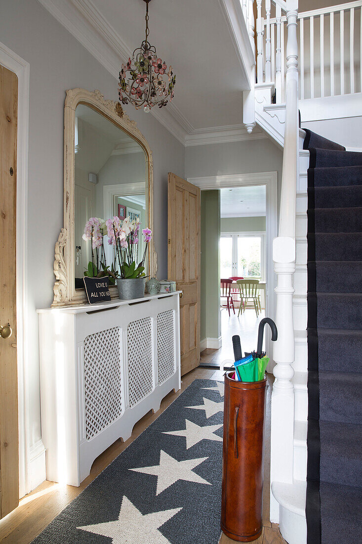 Schirmständer mit sternförmigem Teppichläufer und großem Spiegel im Eingangsflur eines Hauses in Großbritannien