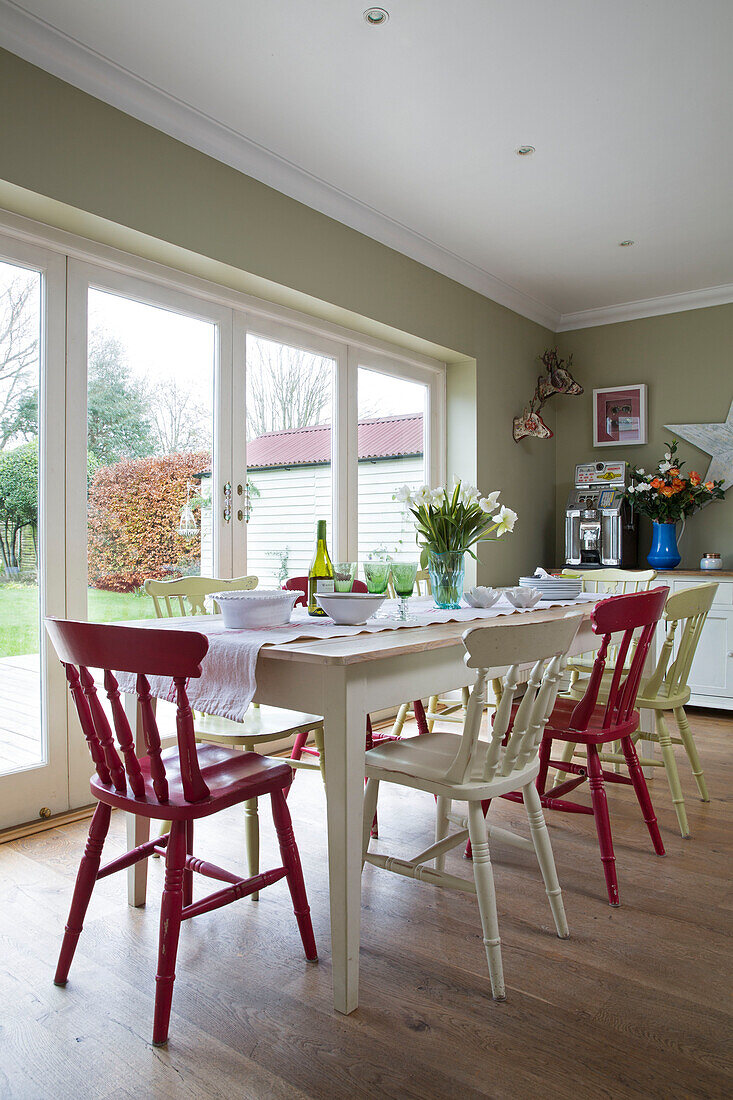 Red and white painted chairs at table in kitchen extension of UK home