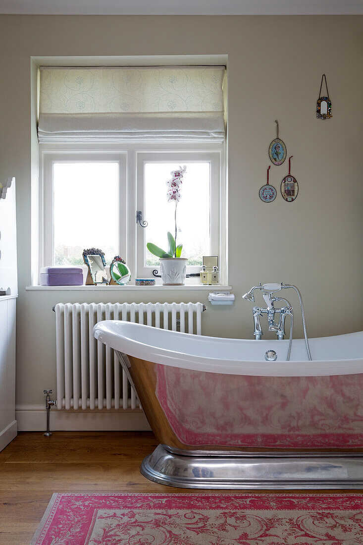 Freestanding chrome bath below window in UK home