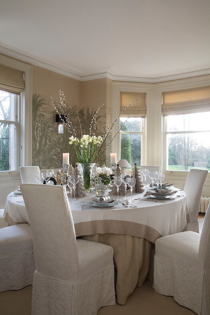 White slip covers on dining chairs at table set for Christmas in Sussex home England UK