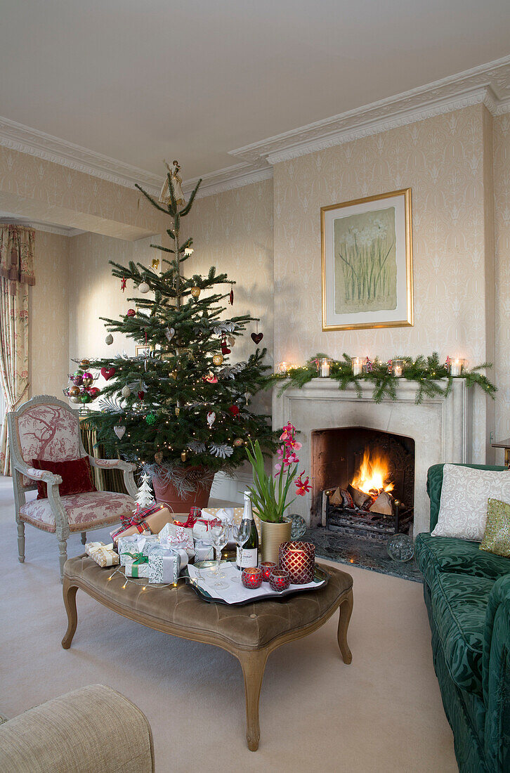 Weihnachtsbaum am Kamin mit Geschenken auf Ottomane in einem Haus in Sussex, England, Vereinigtes Königreich