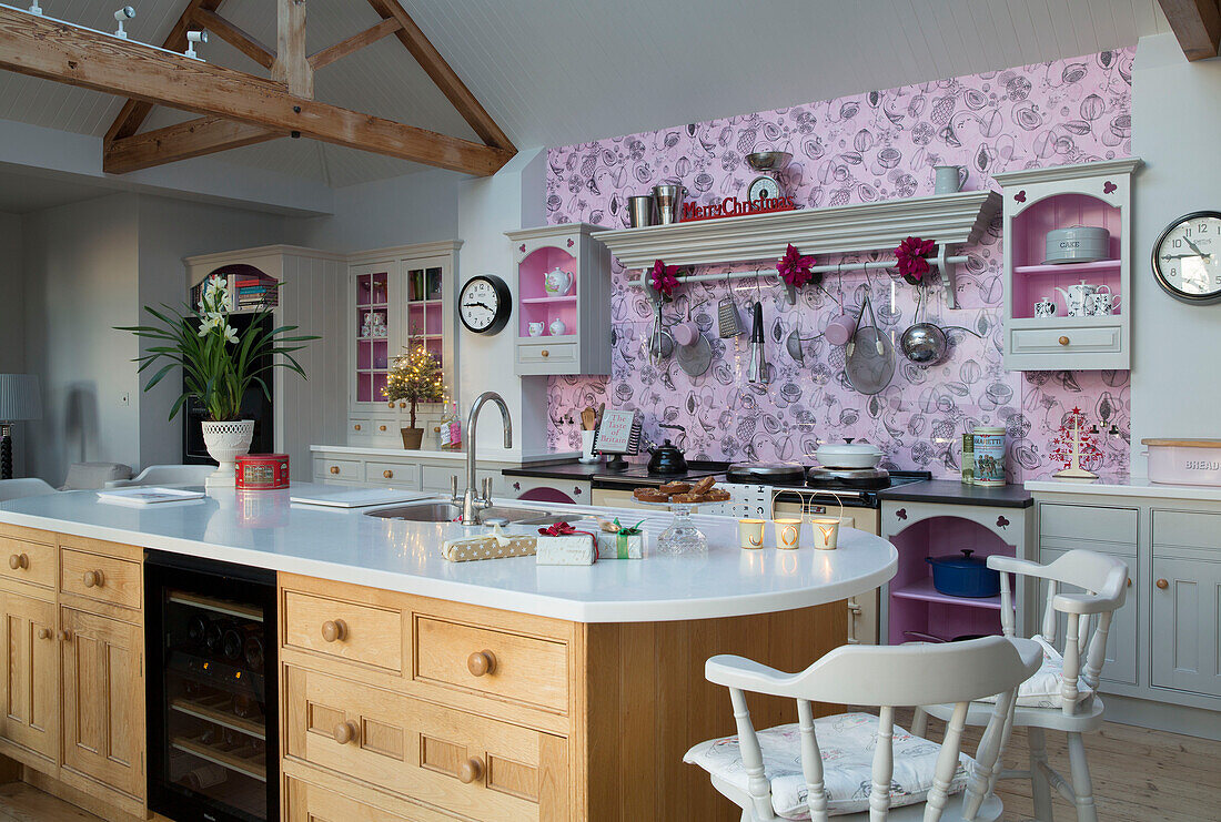 Rosa Wand in offener Küche mit Kochinsel in einem Haus in Sussex England UK