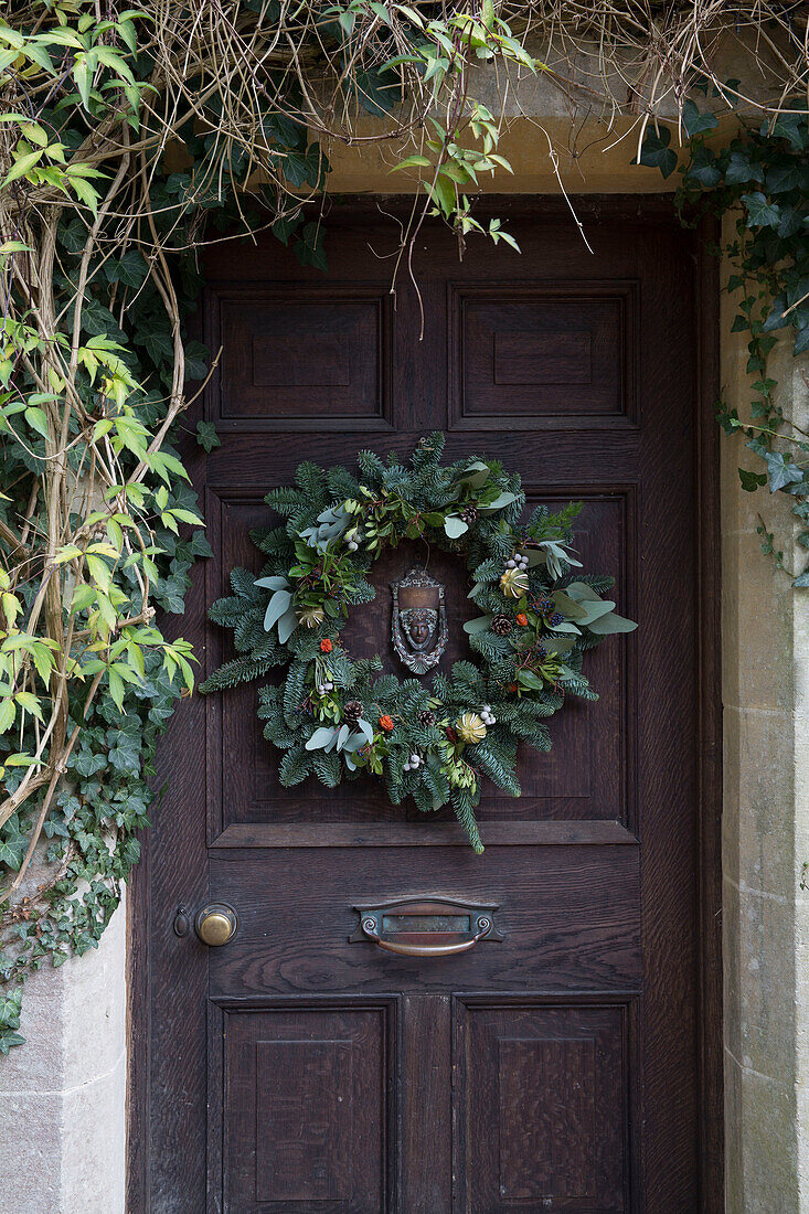 Weihnachtskranz an dunkler Holztür eines Einfamilienhauses in Surrey UK