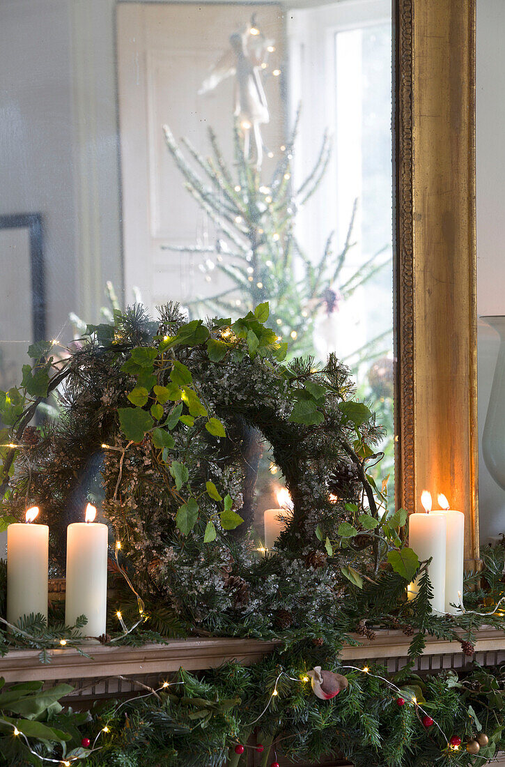 Beleuchtete Kerzen und Weihnachtskränze auf dem Kaminsims in einem Haus in Surrey, England UK