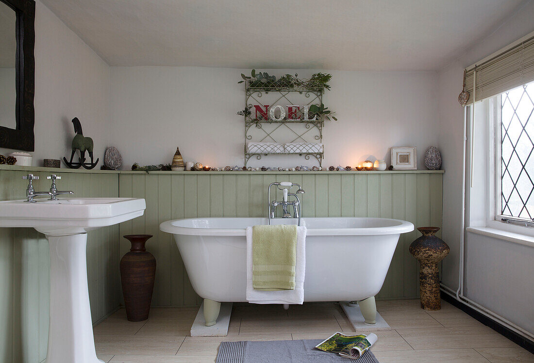 Freistehende Badewanne unter Drahtregal mit Bleiglasfenster und Sockelwaschbecken in einem Haus in Kent, England UK
