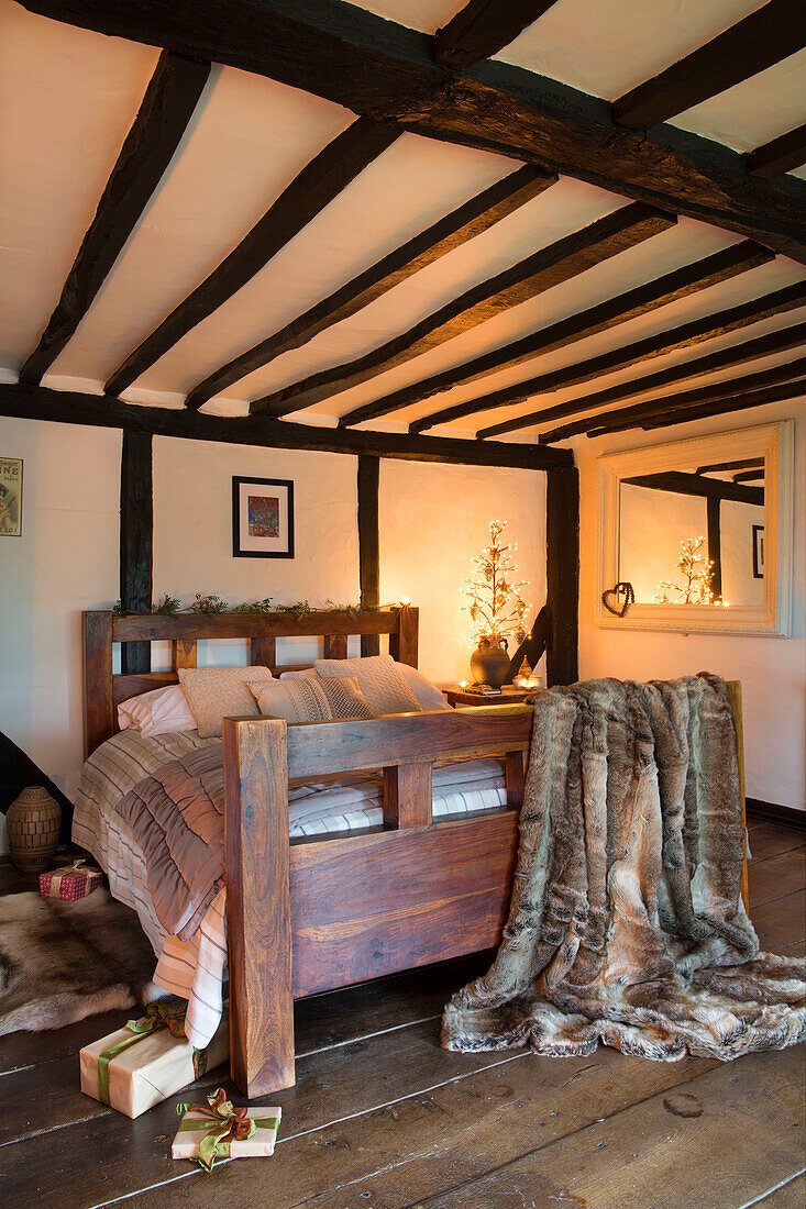 Doppelbett mit Fellüberwurf im Balkenschlafzimmer eines Hauses in Kent, England UK