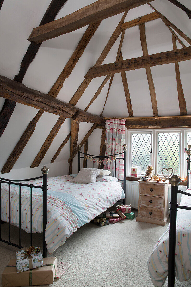 Black metal twin beds in timber framed attic room of Kent home England UK