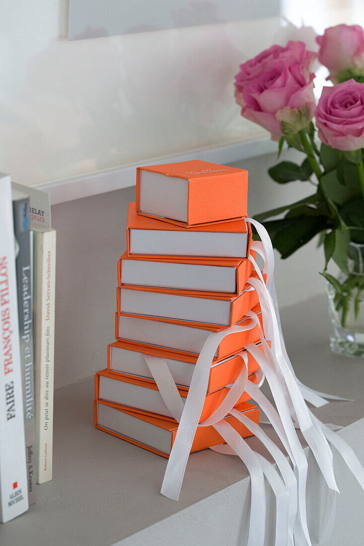 Leuchtend orangefarbene Geschenkboxen mit Rosen und Büchern auf einem Schlafzimmerregal in einem Haus im Südwesten Londons UK