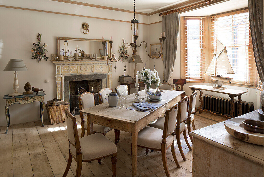 Wooden dining table and chairs with model boat in bay window of Arundel home West Sussex England UK