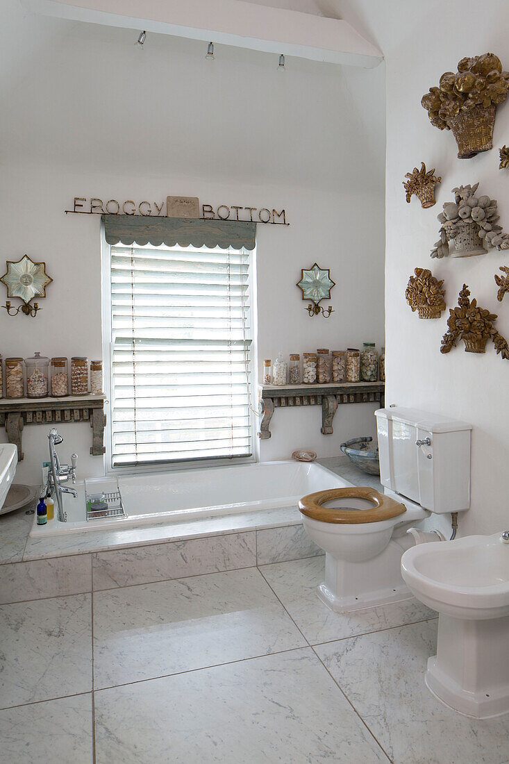 Geschlossene Jalousien über der versenkten Badewanne im gefliesten Badezimmer in Arundel, West Sussex, England, UK