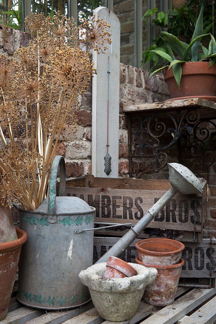 Metal watering can with crates and flower pots in Arundel sun room West Sussex England UK