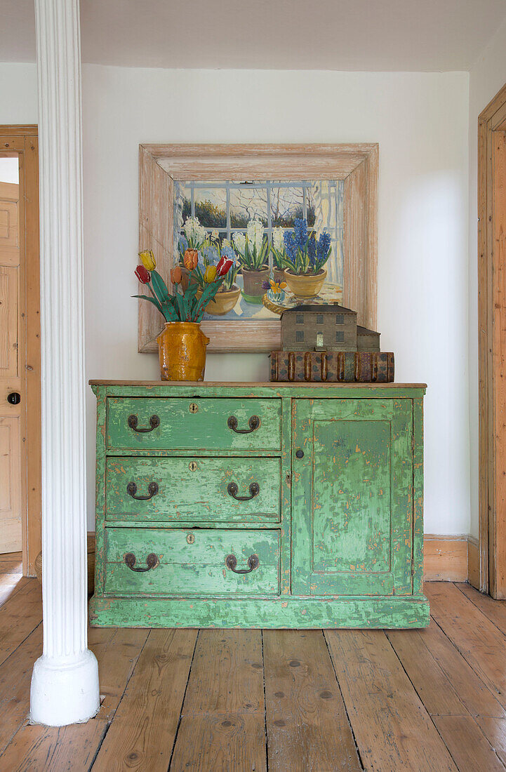 Antique green sideboard with faux tulips in old yellow crock and dollshouse with spring bulb still life painting behind