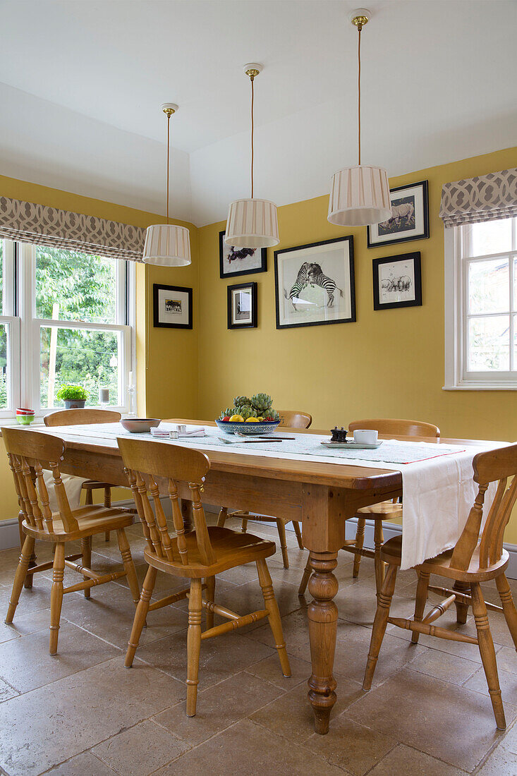 Pendant shades hang above wooden table in yellow dining room of Georgian home Berkshire England UK