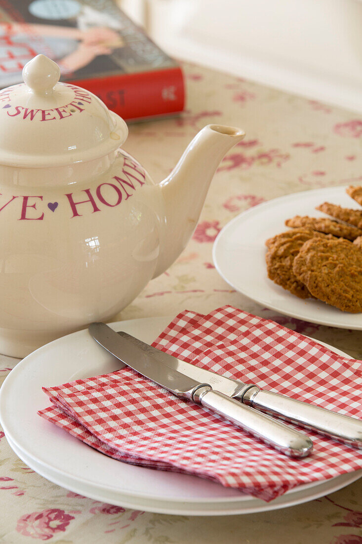 Rotkarierte Servietten und Teekanne mit Keksen auf dem Tisch in einem renovierten viktorianischen Schulhaus, West Sussex, England, UK