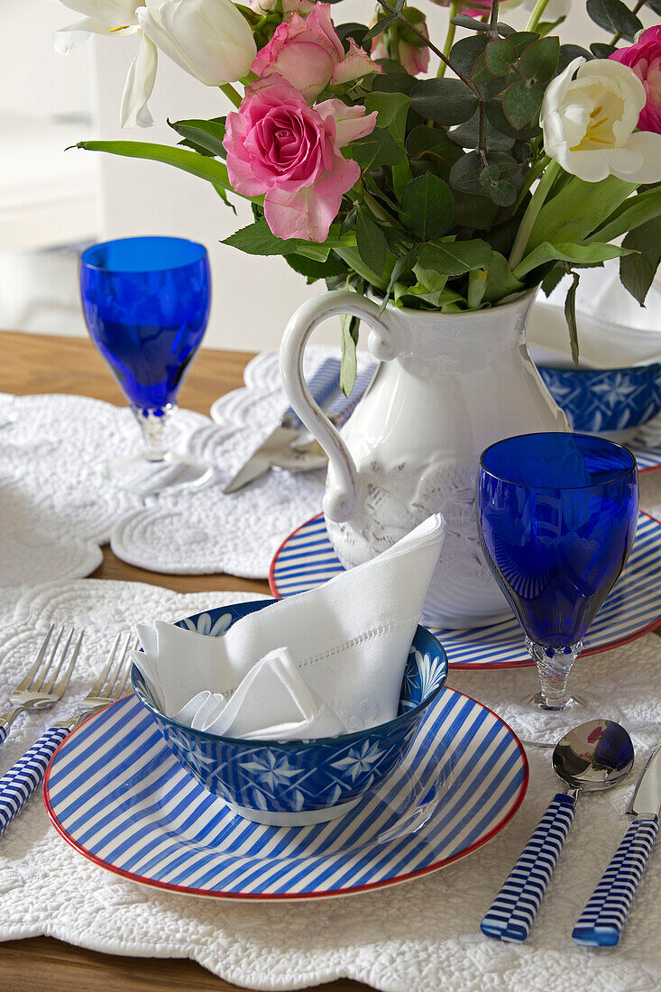 Schnittblumen auf einem Gedeck mit blauen Gläsern auf einem Tisch in einem Londoner Stadthaus UK