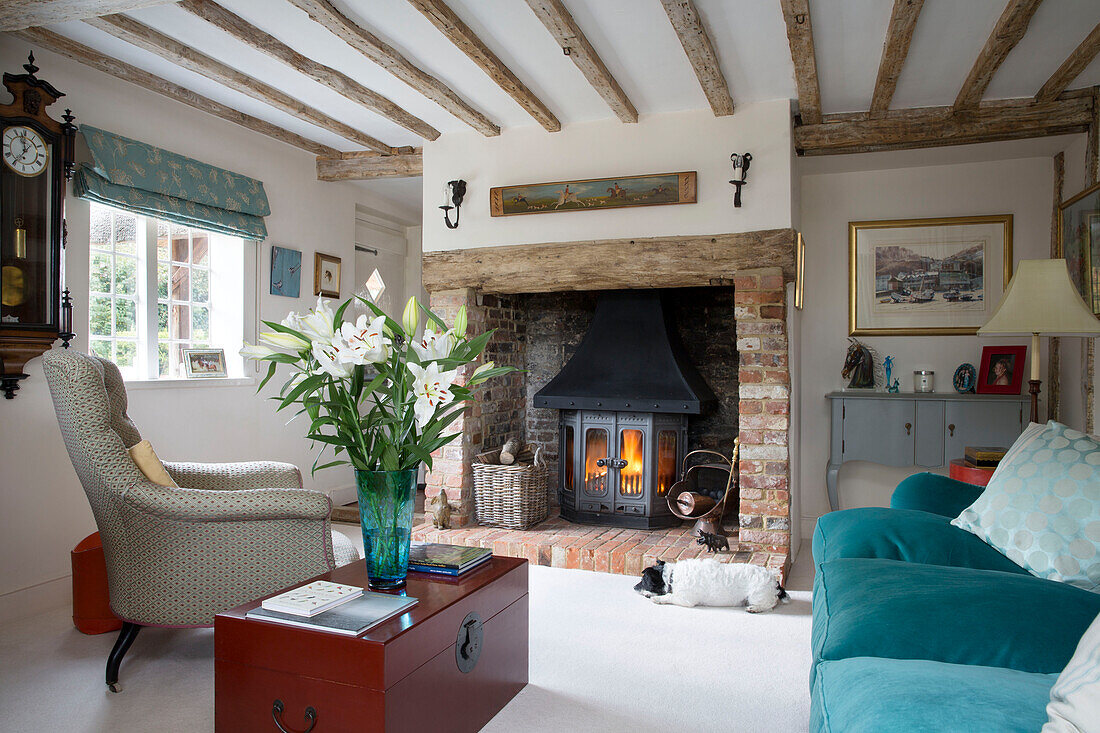 Sessel und Sofa am beleuchteten Kamin in einem unter Denkmalschutz stehenden Cottage in Hampshire England UK
