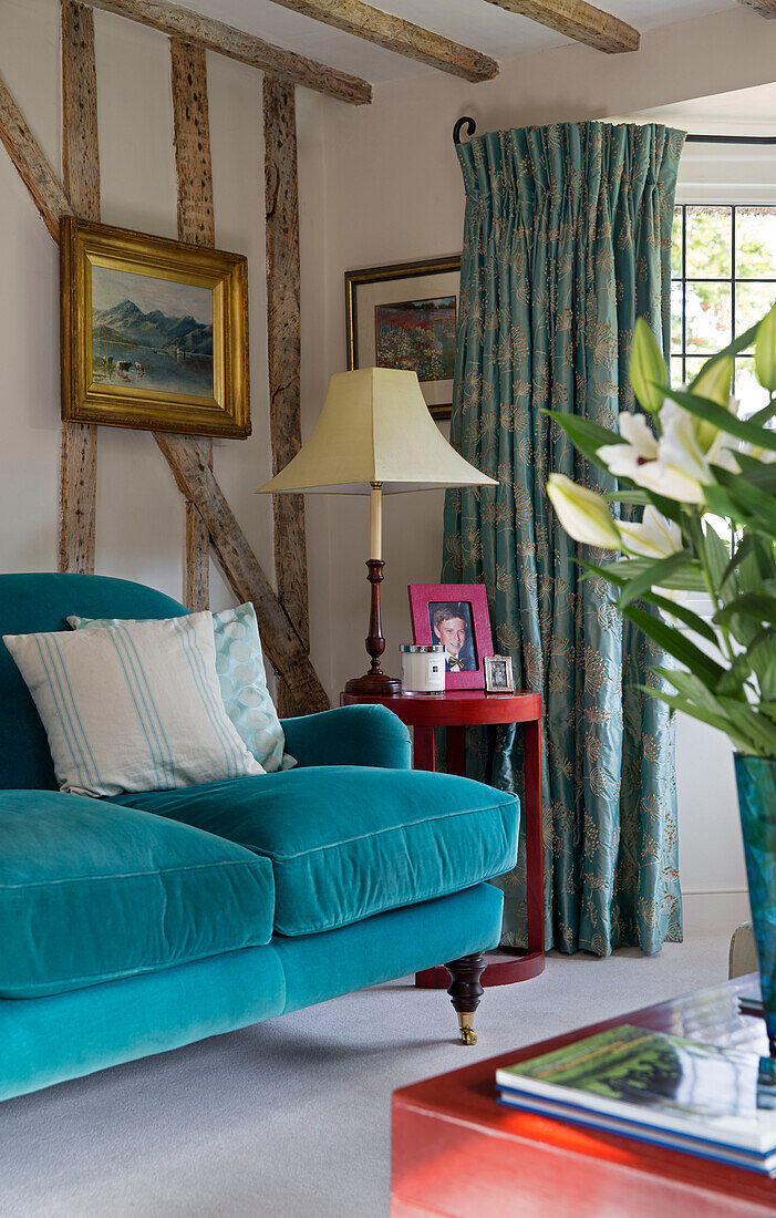 Gilt framed artwork above turquoise sofa in timber-framed Grade II listed cottage in Hampshire England UK