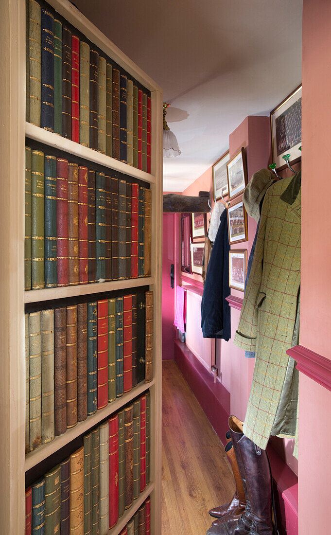 Gebundene Bücher auf einem Regal im Eingangsbereich eines unter Denkmalschutz stehenden Cottage in Hampshire England UK
