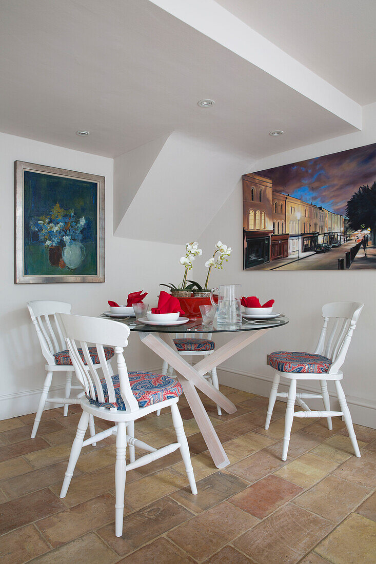 White painted dining chairs at glass topped table in Victorian terraced house London England UK