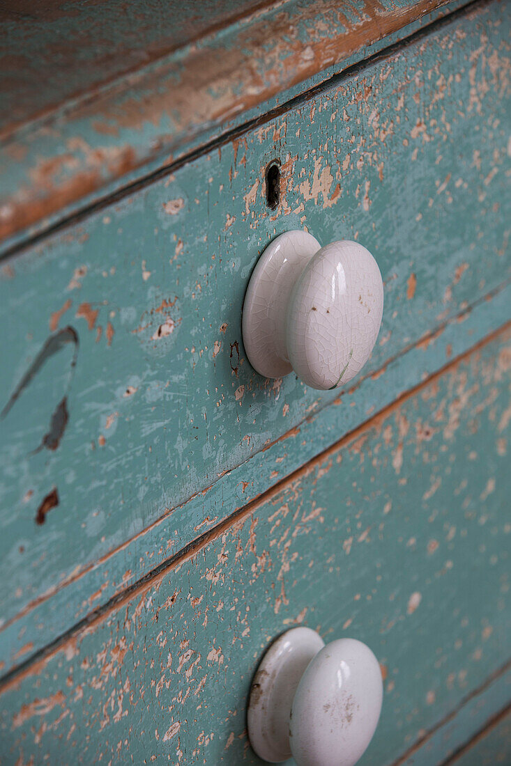 Weiße Schubladengriffe auf verwitterter Kommode in Strandhaus in Sussex, England UK