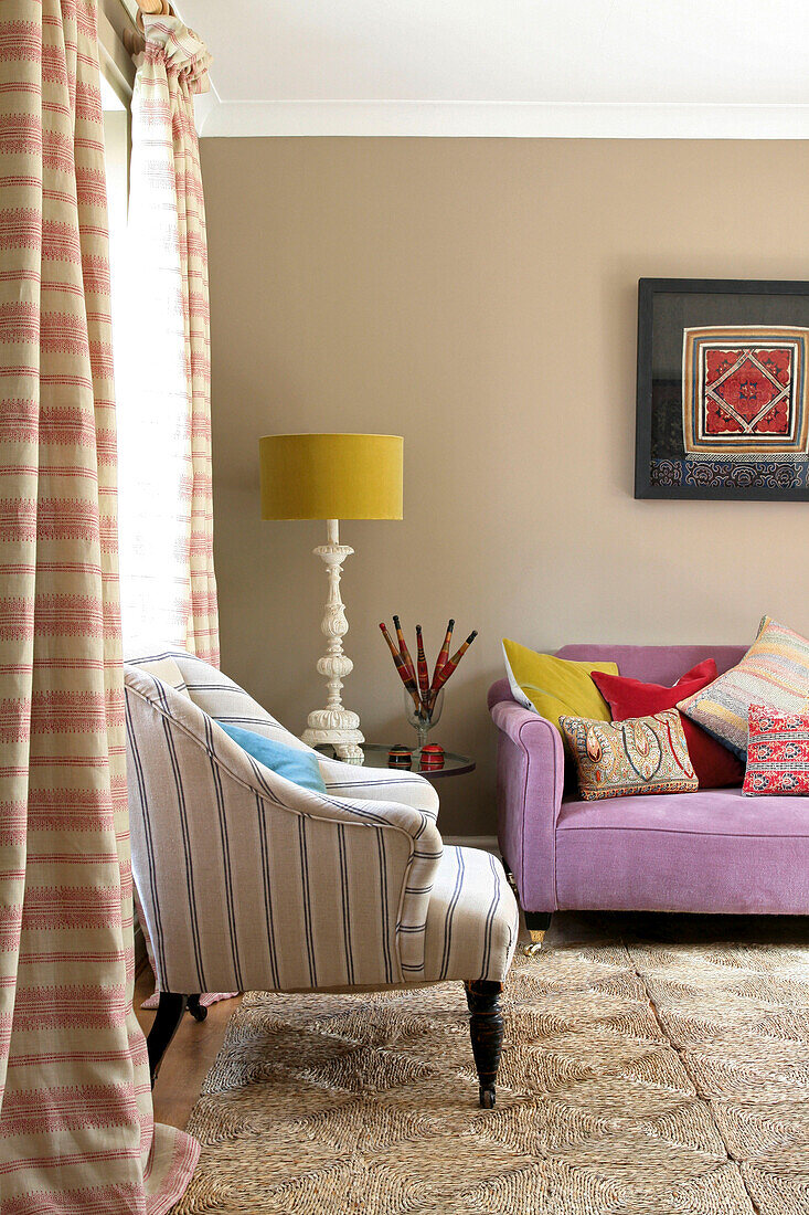 Gestreifter Sessel und Vorhänge mit Kokosmatten im Wohnzimmer eines Hauses in Sussex England UK