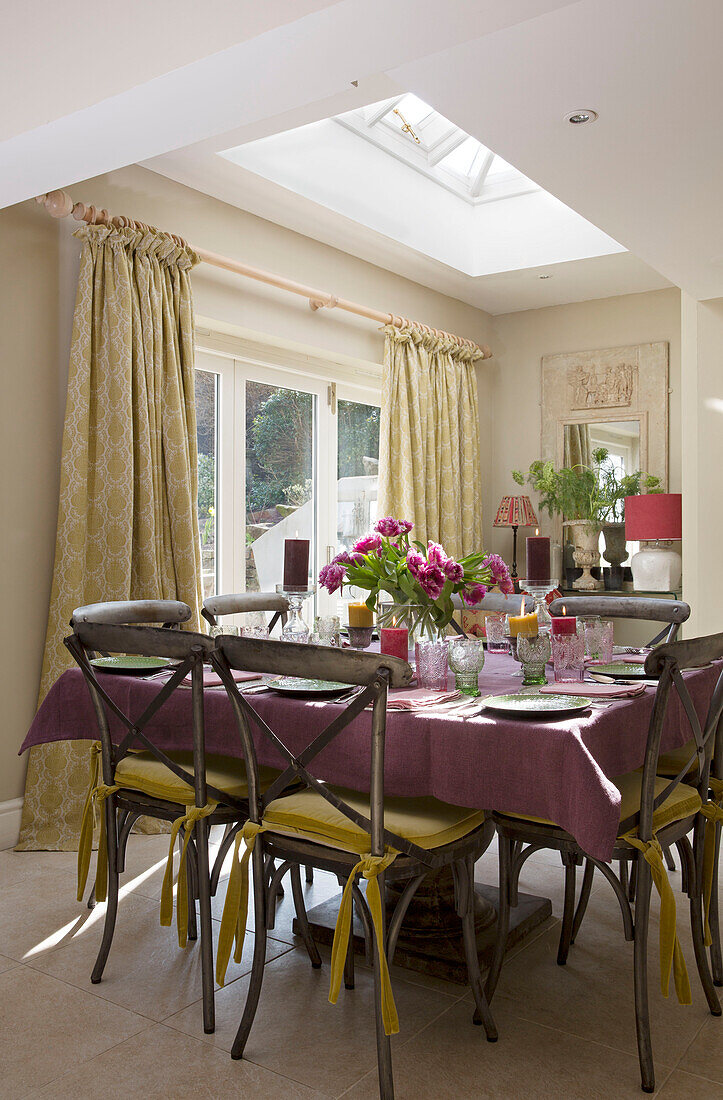Quadratischer Tisch mit violetter Tischdecke in der sonnenbeschienenen Küche eines Hauses in Sussex England UK