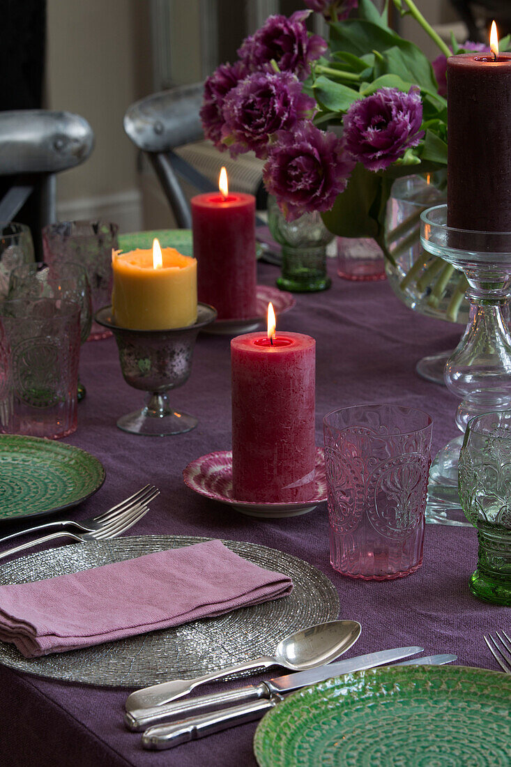 Purple and green place setting with lit candles on Sussex dining table England UK