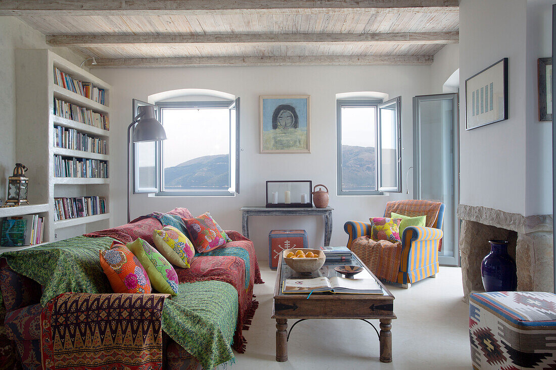 Offene Fenster zum Wohnzimmer mit Bücherregal und stoffbezogenem Sofa in der Villa Ithaca, Griechenland